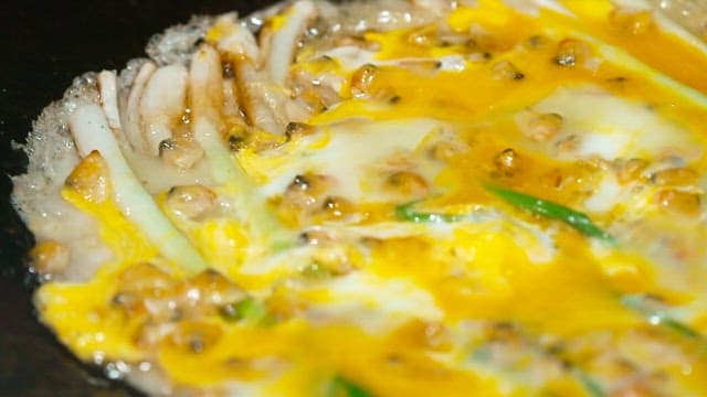 Cooking Korean style pajeon with green onions and fresh clams