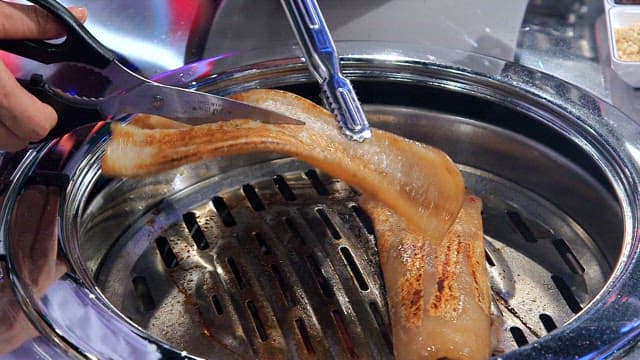 Cooked pork rinds cutting with scissors