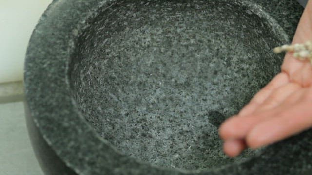 Grinding wheat, the grains in a stone mortar