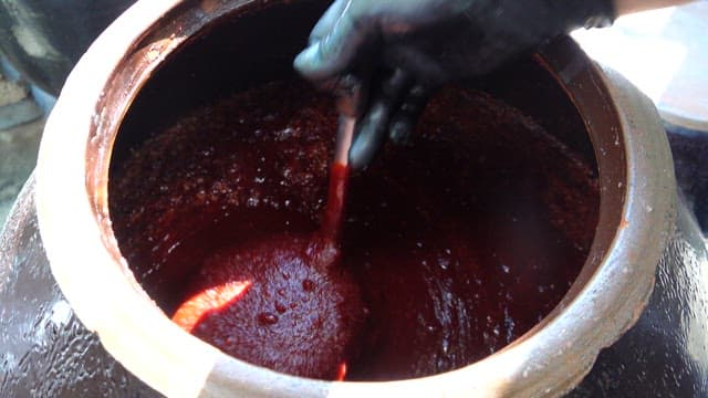 Mixing Thick, Red Chilli Pepper Paste in Ceramic Pot