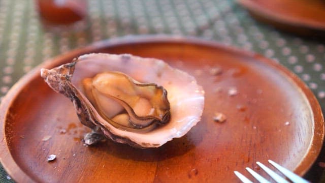 Eating oyster on a wooden plate with lemon juice sprinkled on it