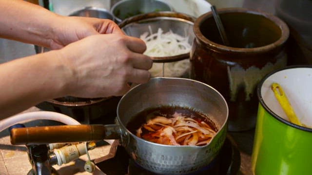 Adding bacon over boiling onions in a small pot