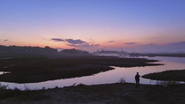Calm river at sunset with a bridge
