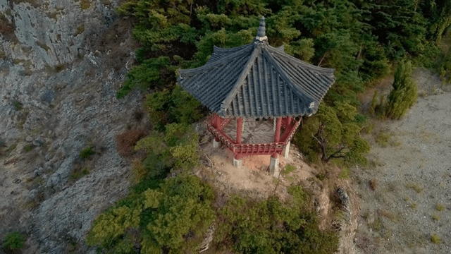 Traditional pavilion on a rocky cliff surrounded by forest