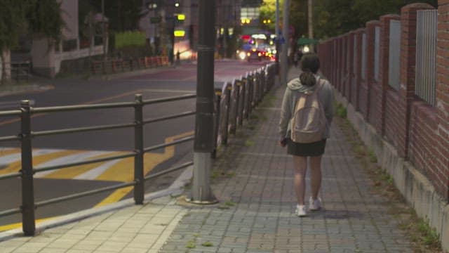 Girl walking alone on a dimly lit street near the school