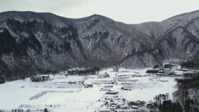 Snow-Covered Village Under Lush Snowy Mountains