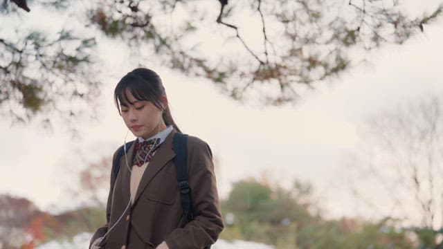 Student walking with earphones in winter