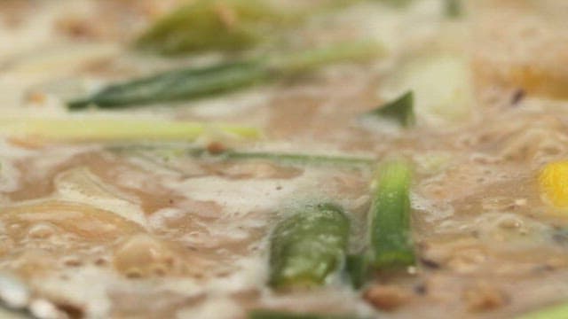 Spoonful of boiling Cheonggukjang with a variety of vegetables and tofu