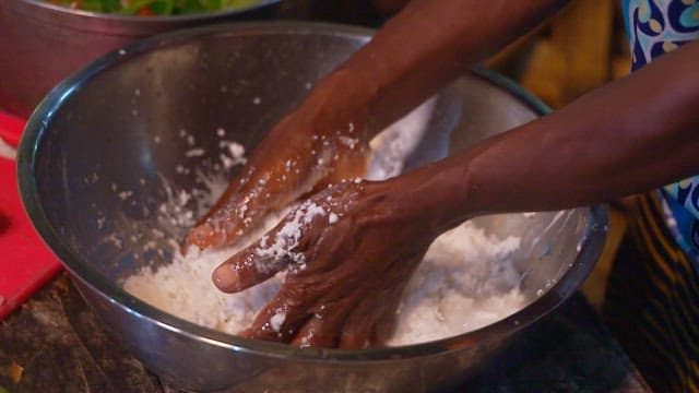 Hand mixing manioc dough in a stainless steel bowl