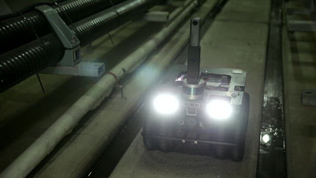 Robot inspecting pipes in a dimly lit industrial setting