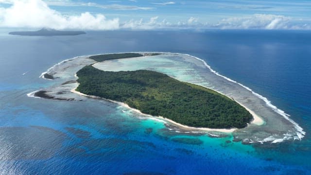 Tropical island with lush greenery and clear blue waters on a sunny day