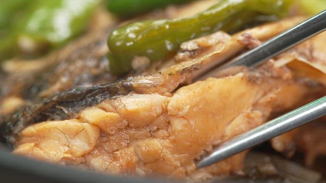 Chopsticks holding a rich piece of fish