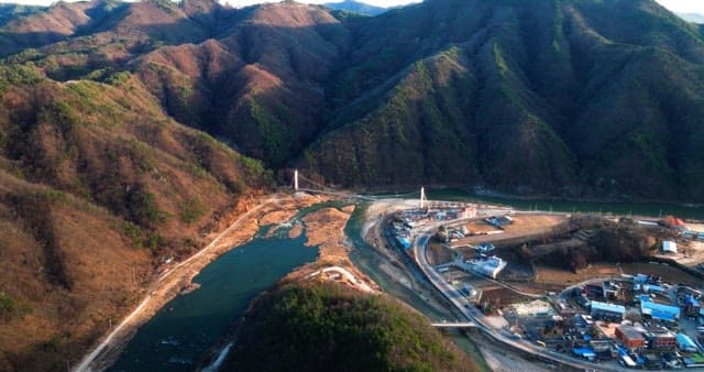 Mountain Village by the River with Suspension Bridge
