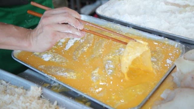 Coating the fish in egg and batter to make fish fritters