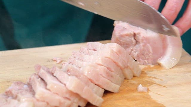 Slicing boiled pork on a cutting board
