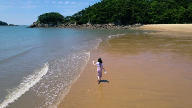 Person Running Barefoot on the Beach on a Sunny Day