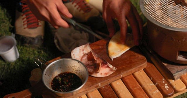 Grilled squid being cut on a wooden cutting board