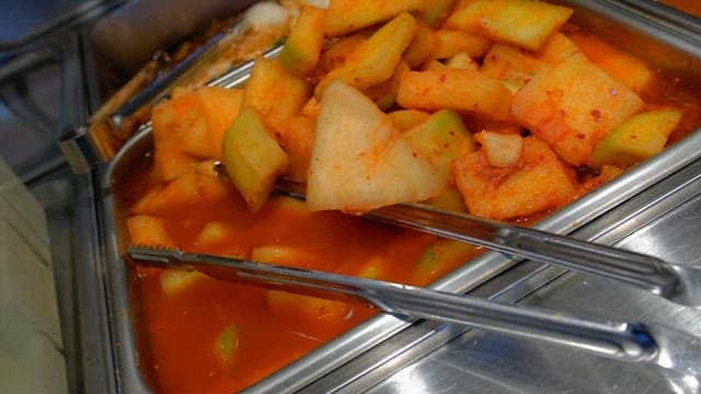 Stainless steel container filled with spicy radish kimchi