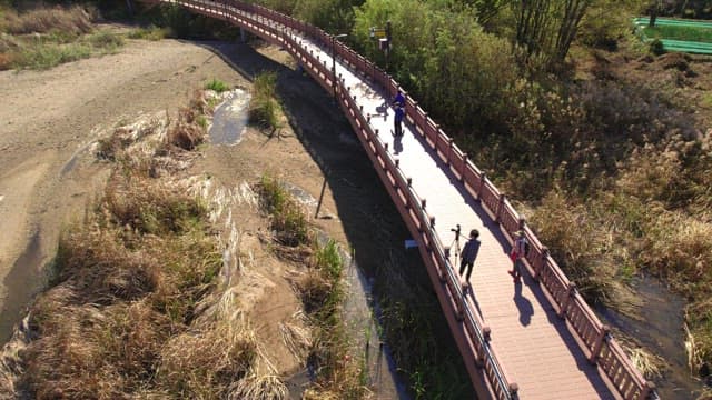 People walking on a wooden boardwalk along the lakeside of Baegunhosu Lake