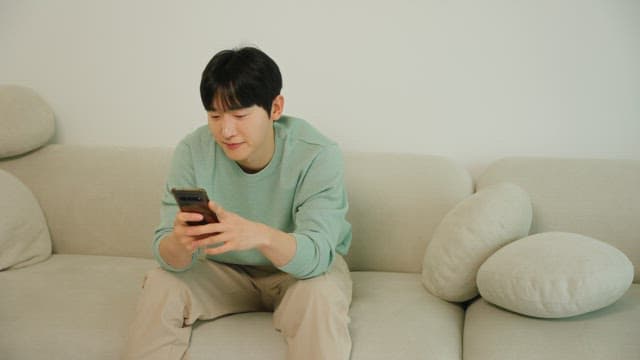 Man seating on a couch using a smartphone