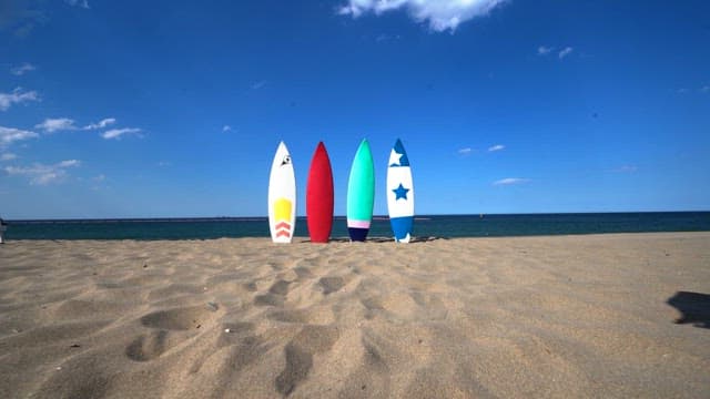 Surfboards arranged on a sandy beach under a clear blue sky