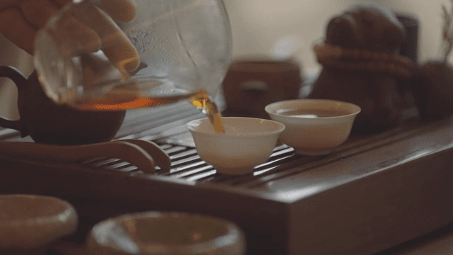 Hand pouring warm tea to a tea cup