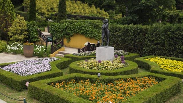 Bronze Statue Among Flower Beds in Park