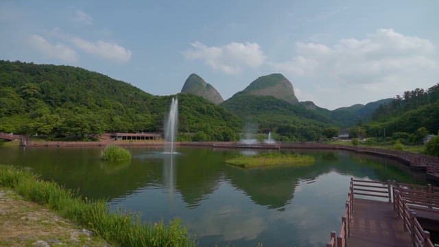 Serene Lake with Fountains and Lush Mountains