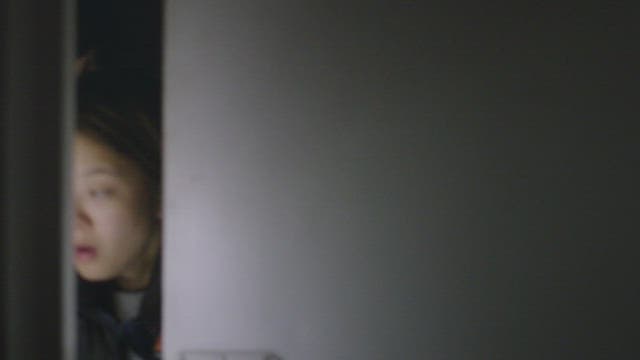 Two women sneaking into a dark room with a flashlight