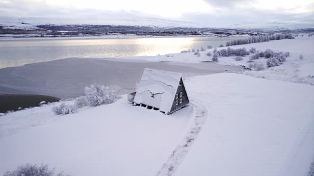 Snowy cabin by a frozen lake