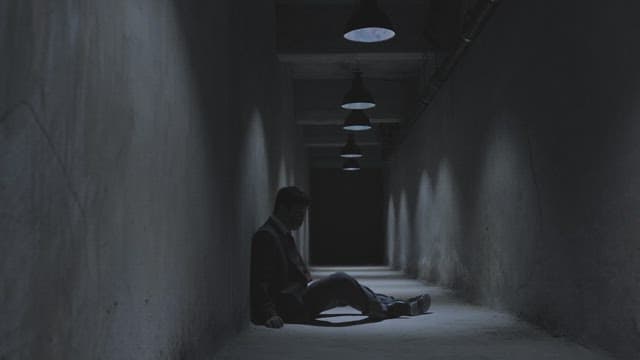 Man staggering up from a dark underground hallway