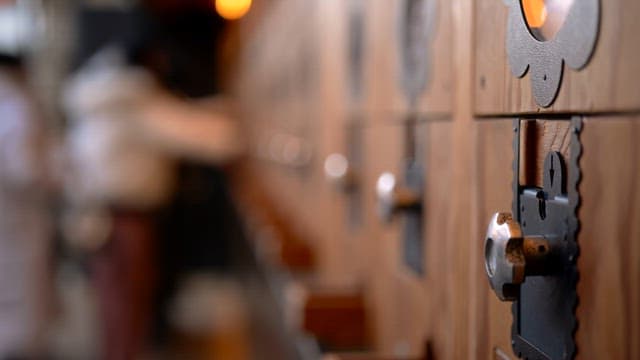 In front of a wooden locker with people crowding around