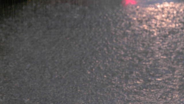Puddle of water on the street where a person with an umbrella is walking