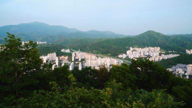 Aerial view of city buildings nestled between lush green mountains
