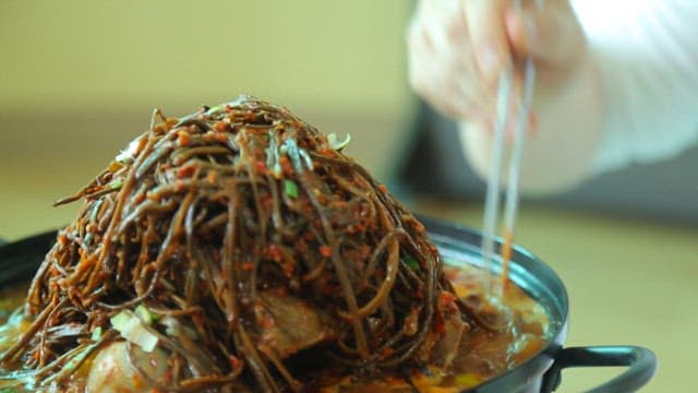 Plate of pork backbone stew topped with sweet potato stem salad