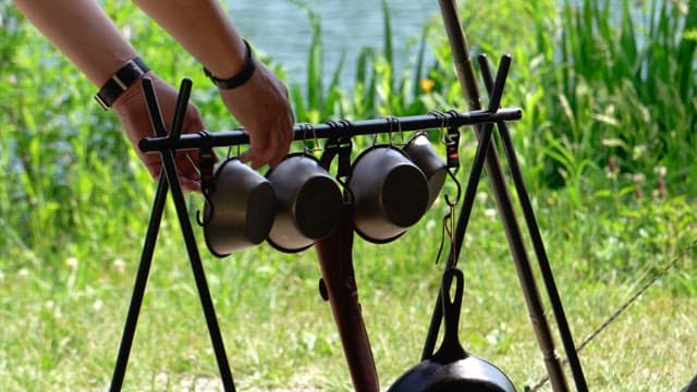 Person removing mugs on an outdoor rack near a lake