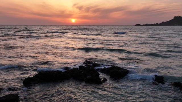 Sunset over a calm ocean with gentle waves