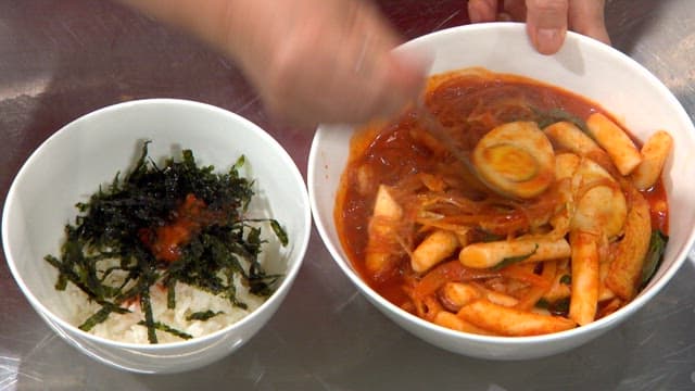 Serving tteokbokki soup with rice with seaweed