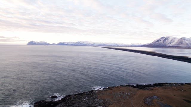 Vast coastal landscape with snowy mountains