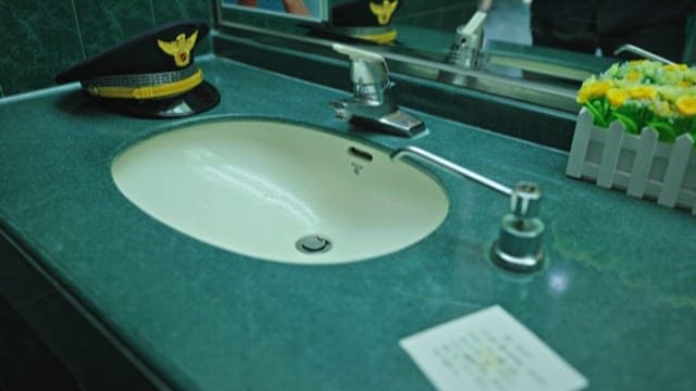Police Officer Adjusting His Uniform in Front of the Bathroom Sink