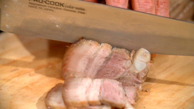 Slicing boiled pork slices on a wooden board