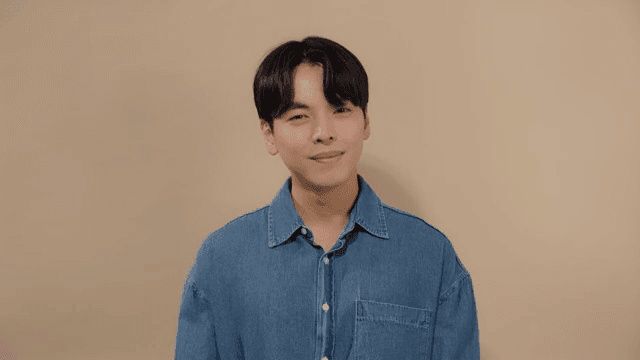 Man in a denim shirt looking straight ahead with a relaxed smile