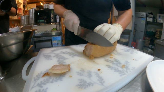 Chef slicing boiled pork in a restaurant kitchen