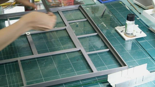 Handling a metal frame on a green grid cutting mat