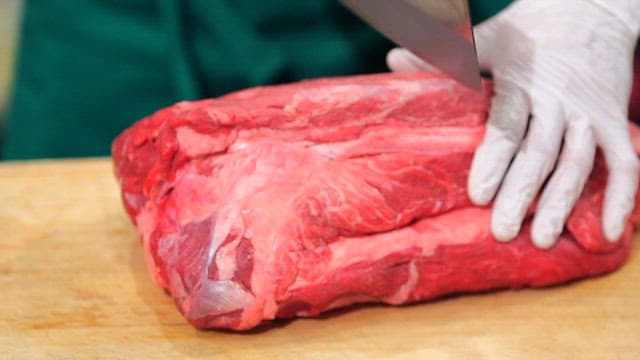 Cutting fresh beef on a wooden board