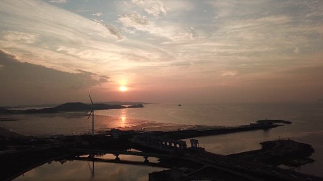 Coastal landscape with wind turbines visible under a sunset sky