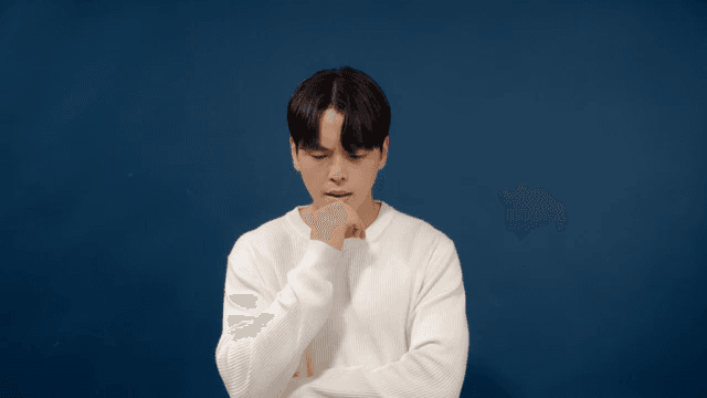 Man in a white sweater with his arms crossed and a serious expression on his face