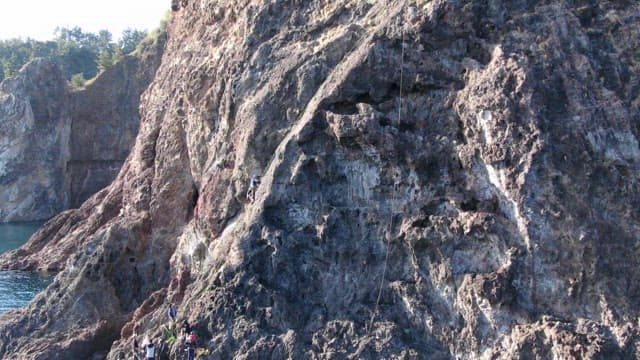 Climber Ascending a Rocky Cliff