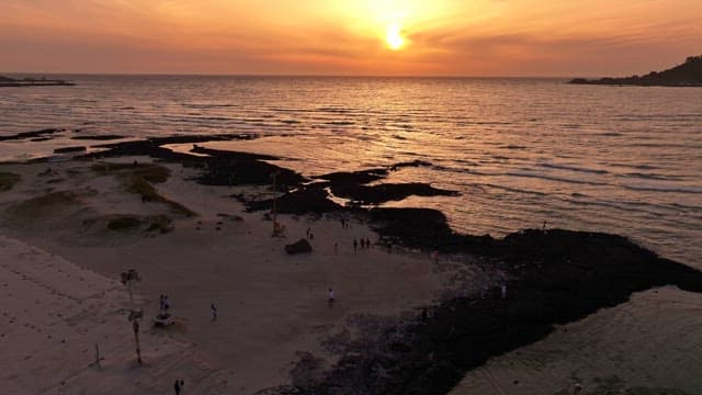 Sunset over a rocky beach with people