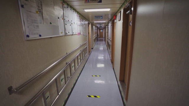 Long corridor in ship with bulletin boards and doors
